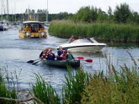 Canoes charge down river with the Dolphin Trus boat in the background